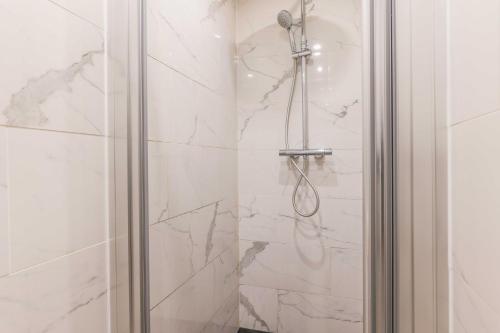 La salle de bains est pourvue d'une douche et de murs en marbre blanc. dans l'établissement Cosy flat - 1BR-4P - Near Nation, à Paris