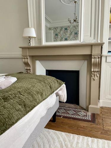 - une chambre avec une cheminée, un lit et un miroir dans l'établissement Le grand Louis, hypercentre, à Cherbourg en Cotentin