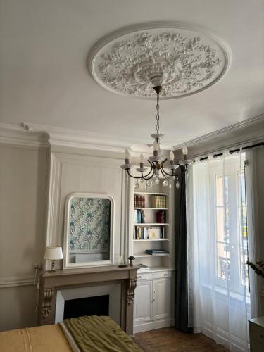 une chambre avec une cheminée et un lustre au plafond dans l'établissement Le grand Louis, hypercentre, à Cherbourg en Cotentin