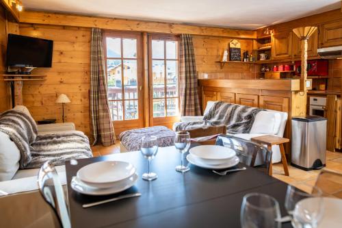 - un salon doté d'une table avec des assiettes et des verres à vin dans l'établissement Warm 2-bedroom apartment near the Tourist Office, à Megève