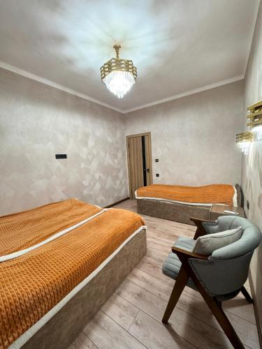 a bedroom with two beds and a chair and a chandelier at Mountain paradise Премиум дача в Чимгане in Chimgan