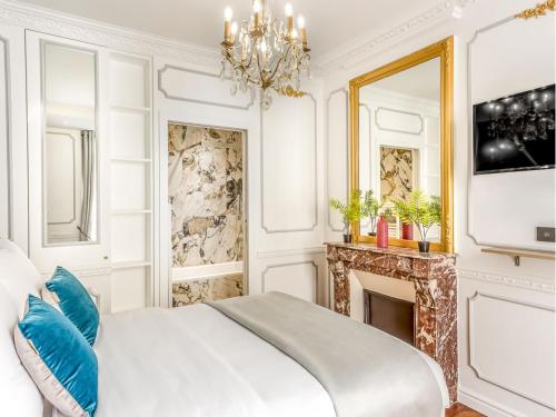 - une chambre blanche avec un lit et un lustre dans l'établissement Merveil - Luxury Suite - Louvre - Sebastopol II, à Paris