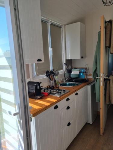 une cuisine avec des armoires blanches et un comptoir dans l'établissement la petite maison verte, à Plévin