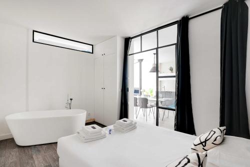 La salle de bains blanche est pourvue d'une baignoire et d'une grande fenêtre. dans l'établissement Luminous apartment 4P2BD Sacré-Coeur Montmartre - G, à Paris