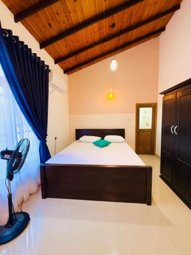 a bedroom with a large bed with a wooden ceiling at Kanapathiy Rest House in Trincomalee
