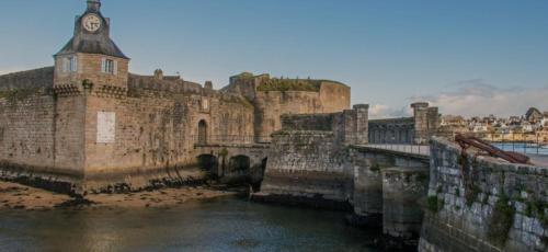 a large castle with a clock tower and water at Chambre paisible avec jardin à la campagne en Finistère sud in Scaër