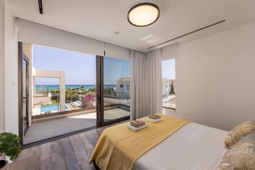 a bedroom with a large bed and a large window at Villa JoJo Seafront in Ayia Napa