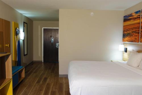 a bedroom with a large white bed and a door at Days Inn by Wyndham Norman in Norman
