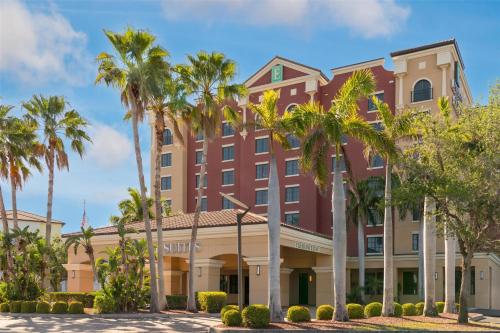 a hotel with palm trees in front of it at Embassy Suites Fort Myers - Estero in Estero