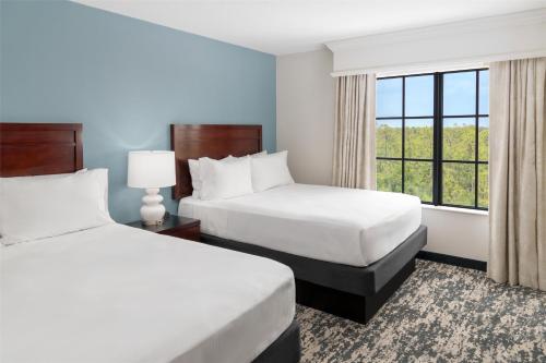 two beds in a hotel room with a window at Embassy Suites Fort Myers - Estero in Estero