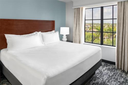 a large bed in a room with a large window at Embassy Suites Fort Myers - Estero in Estero