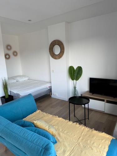 - un salon avec un canapé bleu et un lit dans l'établissement Studio cosy avec terrasse à deux pas de la gare, à Amiens