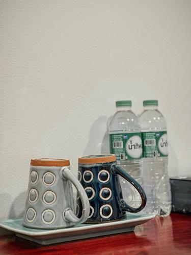 a plate with two coffee mugs and bottles of water at Hometown Stays Hatyai in Hat Yai