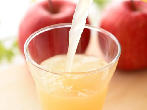 a glass of orange juice with apples in the background at Comfort Inn Niigata Kameda in Niigata