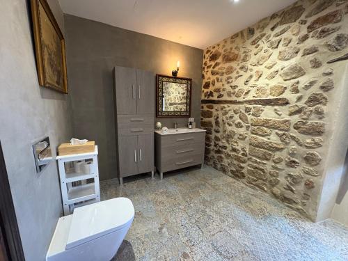 a bathroom with a toilet and a stone wall at Casa Histórica con Piscina Sauna y Jacuzzi in Lloseta