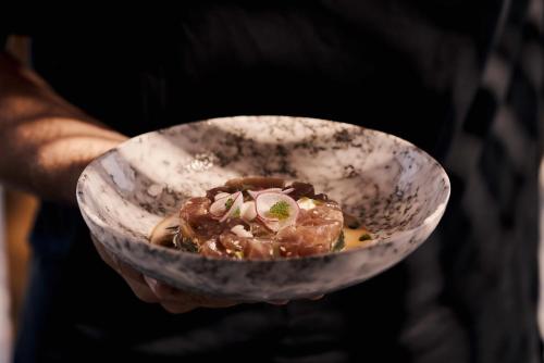 a person is holding a bowl of food at Magma Resort Santorini, In The Unbound Collection By Hyatt in Vourvoulos