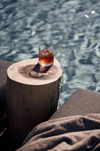 a glass of tea sitting on a table next to a pool at Magma Resort Santorini, In The Unbound Collection By Hyatt in Vourvoulos