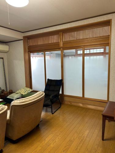 a living room with a couch and a chair and windows at Rom's Inn in Wakimachi