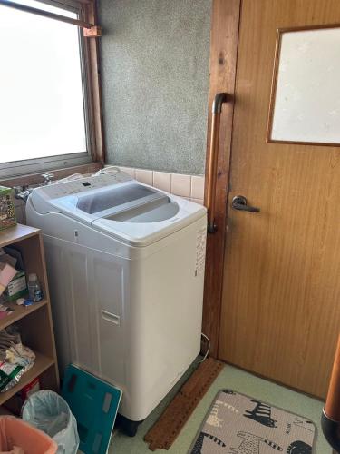 a washer and dryer in a room with a door at Rom's Inn in Wakimachi