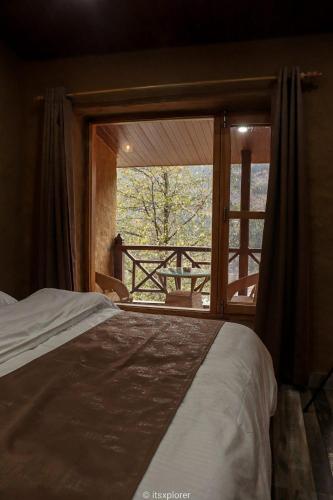 a bedroom with a bed and a large window at Basho Mud Huts in Vashisht