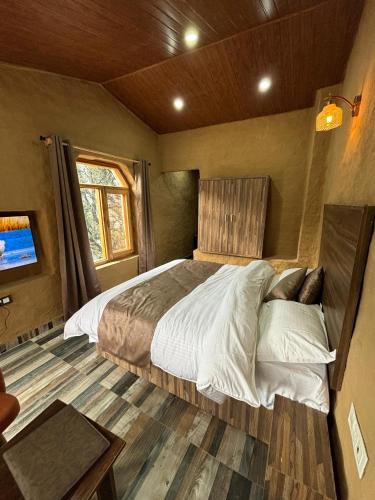 a bedroom with a large bed in a room at Basho Mud Huts in Vashisht