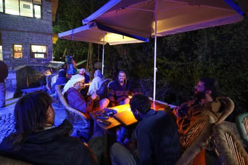 a group of people sitting around a table under an umbrella at Basho Mud Huts in Vashisht