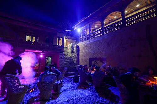 a group of people sitting in a room at night at Basho Mud Huts in Vashisht