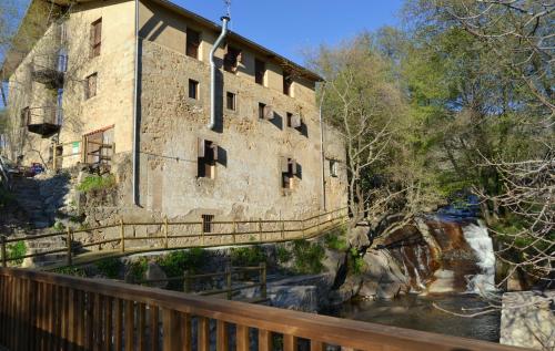 a bridge over a river in front of a building at Albergue Aurora Boreal in Casas del Monte