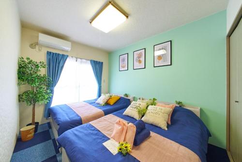 two beds in a room with blue walls at AO303 - Tokyo Stay Spacious Apartment Direct Train to Narita & Asakusa in Tokyo