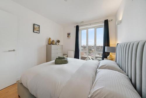 ein weißes Schlafzimmer mit einem großen Bett und einem Fenster in der Unterkunft Modern and central 1BR Flat with Skyline View in London