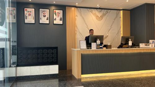 a man sitting at a counter in a lobby at Uptown Hotel Apartments Abu Dhabi by Gewan in Abu Dhabi