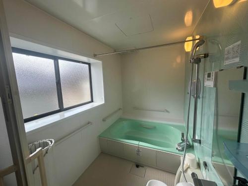 a bathroom with a bath tub and a window at Spacious Traditional Japanese house by Restavio in Ozu