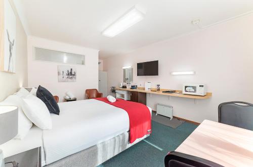 a hotel room with two beds and a desk at City Heart Motel Warrnambool in Warrnambool