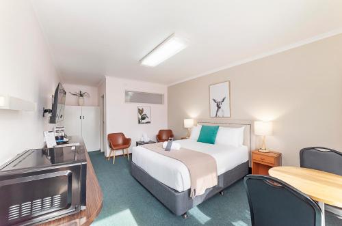 a hotel room with a bed and a table and chairs at City Heart Motel Warrnambool in Warrnambool