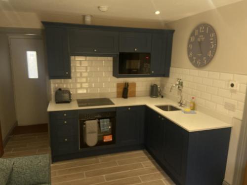 a kitchen with black cabinets and a clock on the wall at Durham City Cottages in Durham
