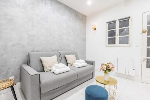 - un salon avec un canapé gris et un vase de fleurs dans l'établissement CMG - LE MARAIS/SAINT ANTOINE, à Paris
