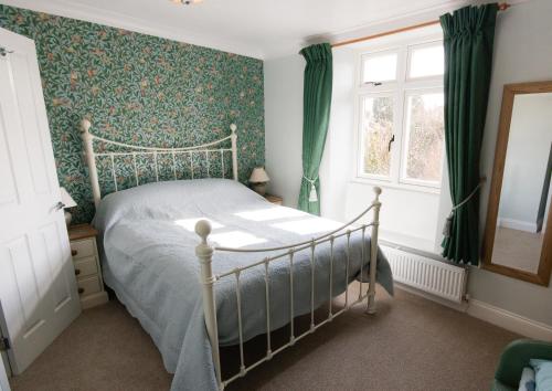 a bedroom with a bed with green wallpaper at The School House in Bridgwater
