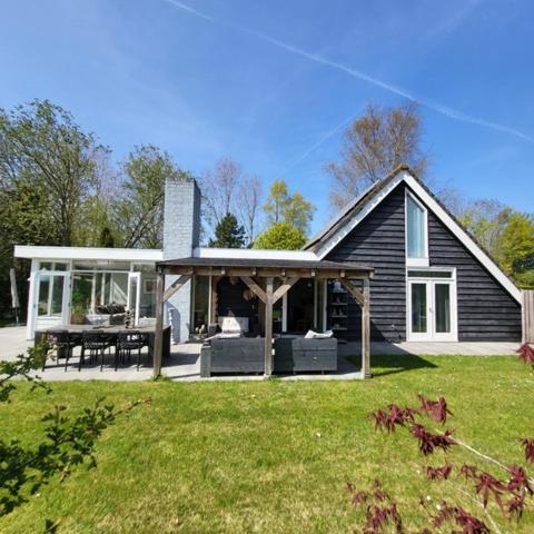 a black house with a porch and a patio at Vakantiehuis met sauna, omheinde tuin & nabij strand VP087 in Bruinisse