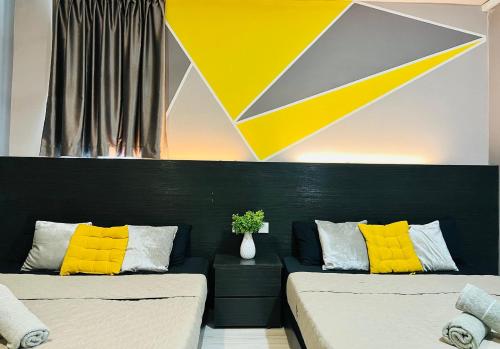 two beds with yellow pillows in a room at M Suite Homestay, Sutera Avenue Kota Kinabalu - Near Imago in Kota Kinabalu