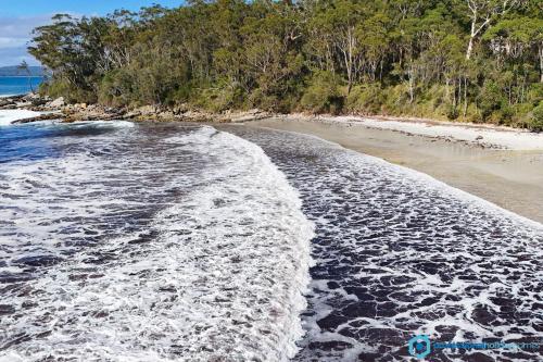 an empty beach with waves crashing on the shore at High Tide - Pet Friendly with Fire Pit in Sanctuary Point