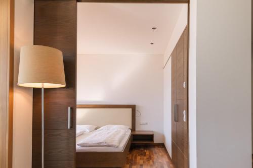 a small bedroom with a bed and a mirror at Appartement KroneLiving in Tirolo