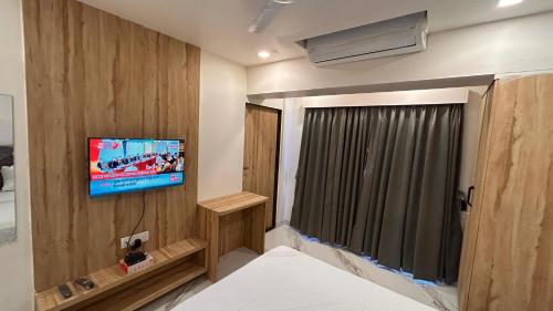 a bedroom with a tv on the wall and a bed at Shree Nidhi Residency in Navi Mumbai