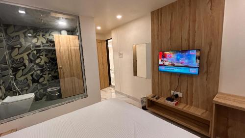 a bedroom with a bed and a tv on a wall at Shree Nidhi Residency in Navi Mumbai