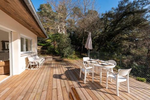 a wooden deck with a table and chairs and an umbrella at T3 Grande Terrasse Vue Foret in Soorts-Hossegor