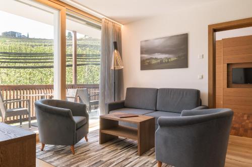 a living room with a couch and chairs and a television at Appartement KroneLiving in Tirolo