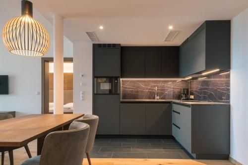 a kitchen with black cabinets and a wooden table at Appartement KroneLiving in Tirolo