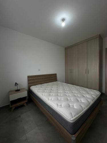 a bedroom with a large bed and a cabinet at Oroklini's Flat in Larnaka