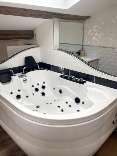 une baignoire blanche dans une salle de bain avec un miroir dans l'établissement Escapade Romantique & Balnéo, à Riom