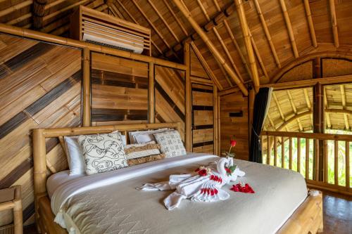 a bedroom with a bed in a wooden cabin at Damuh Alam in Lovina