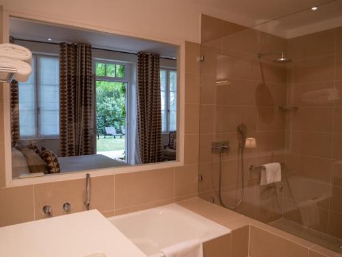 a bathroom with a tub and a shower with a mirror at Domaine de la Tortinière in Montbazon
